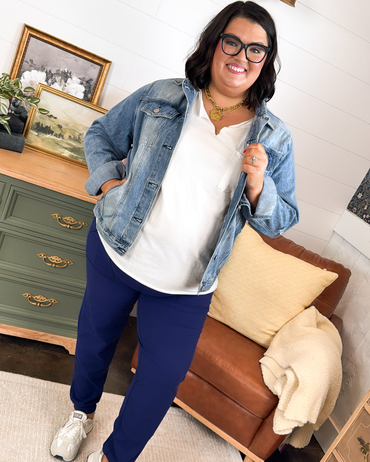 Woman wearing navy high waist joggers with a white top and denim jacket