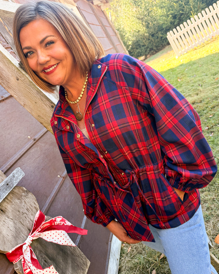 Woman wearing a red and navy plaid jacket with a drawstring waist and snap front styled with jeans
