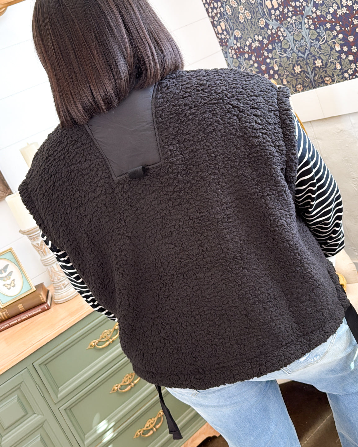 Back view of the black oversized sherpa vest over a striped top
