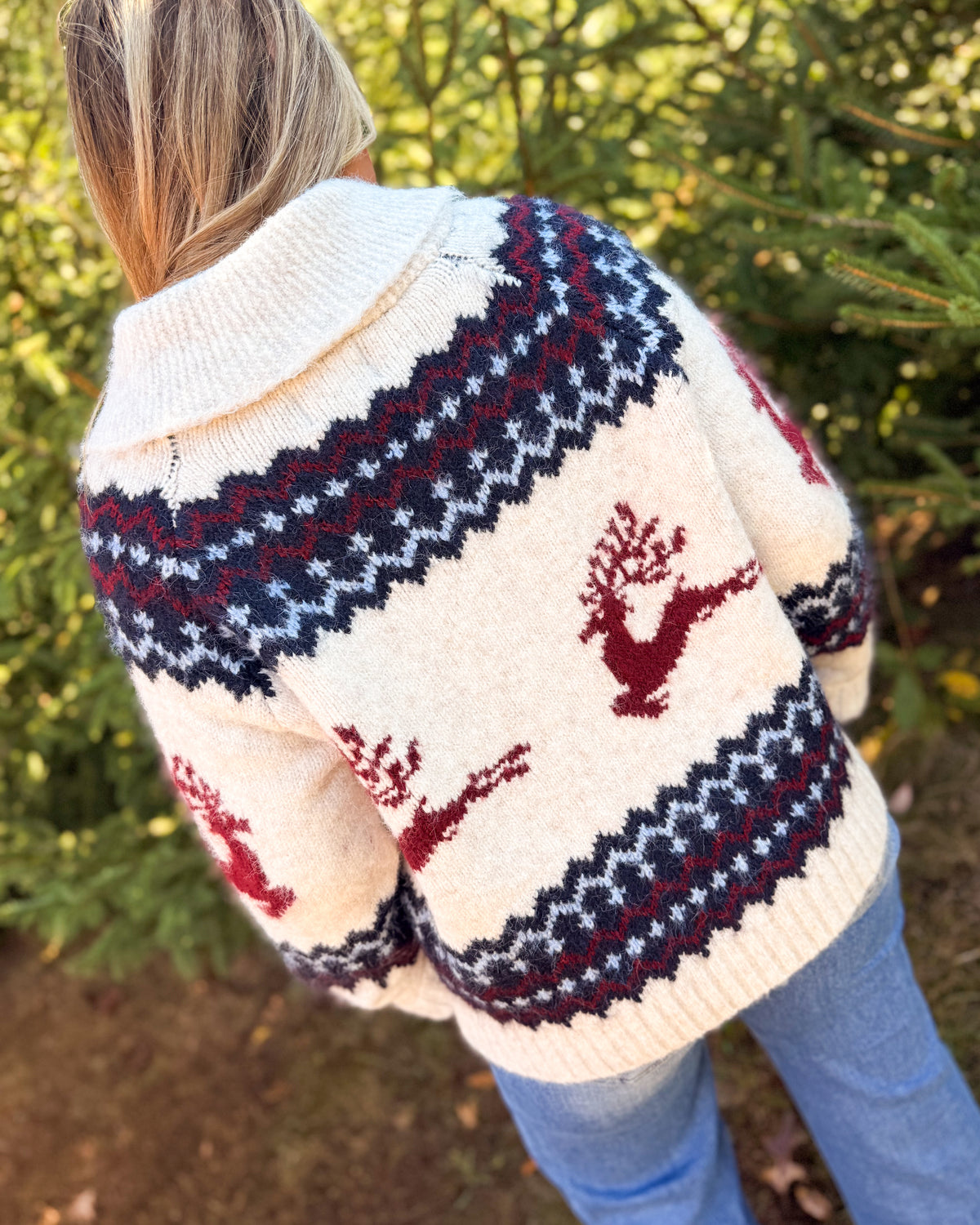 Back view of a cream fair isle sweater cardigan with a navy patterned yoke and red reindeer