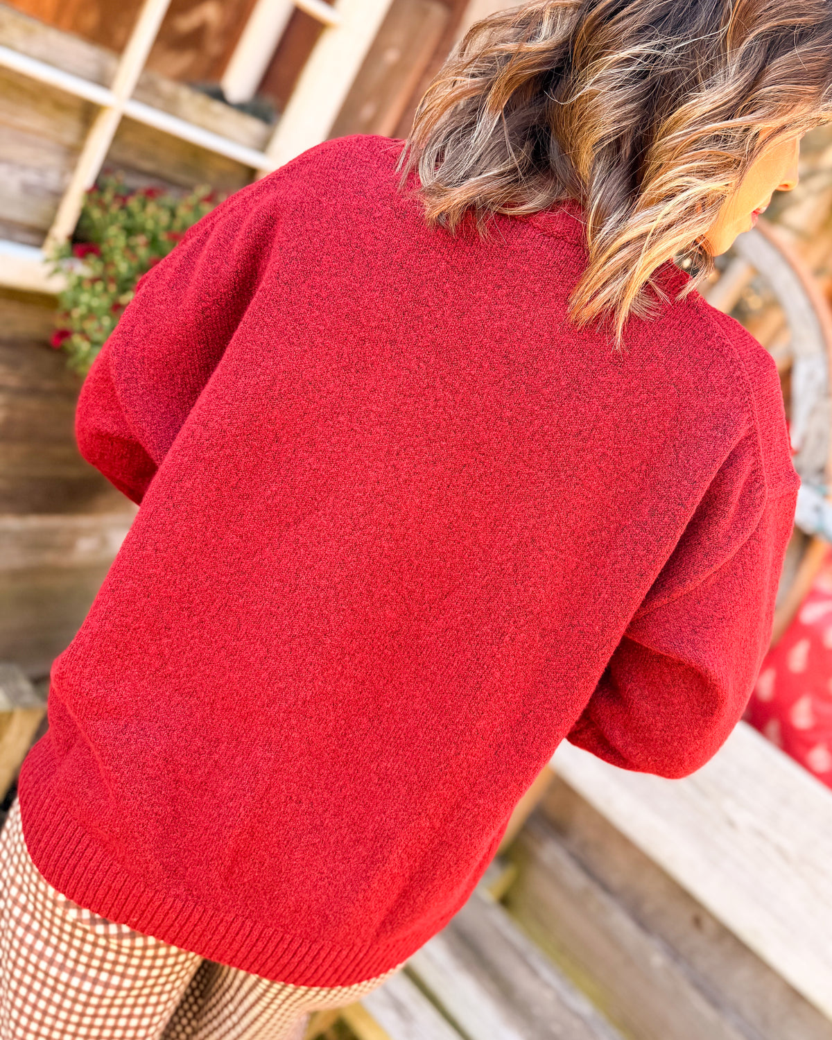 Back view of a red knit sweater styled with houndstooth pants