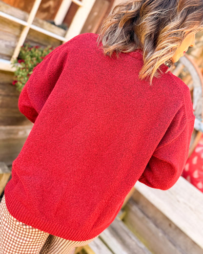 Back view of a red knit sweater styled with houndstooth pants