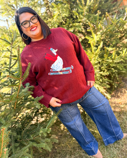 Full-length view of a red Beak Season duck skiing knit sweater styled with medium wash wide leg jeans
