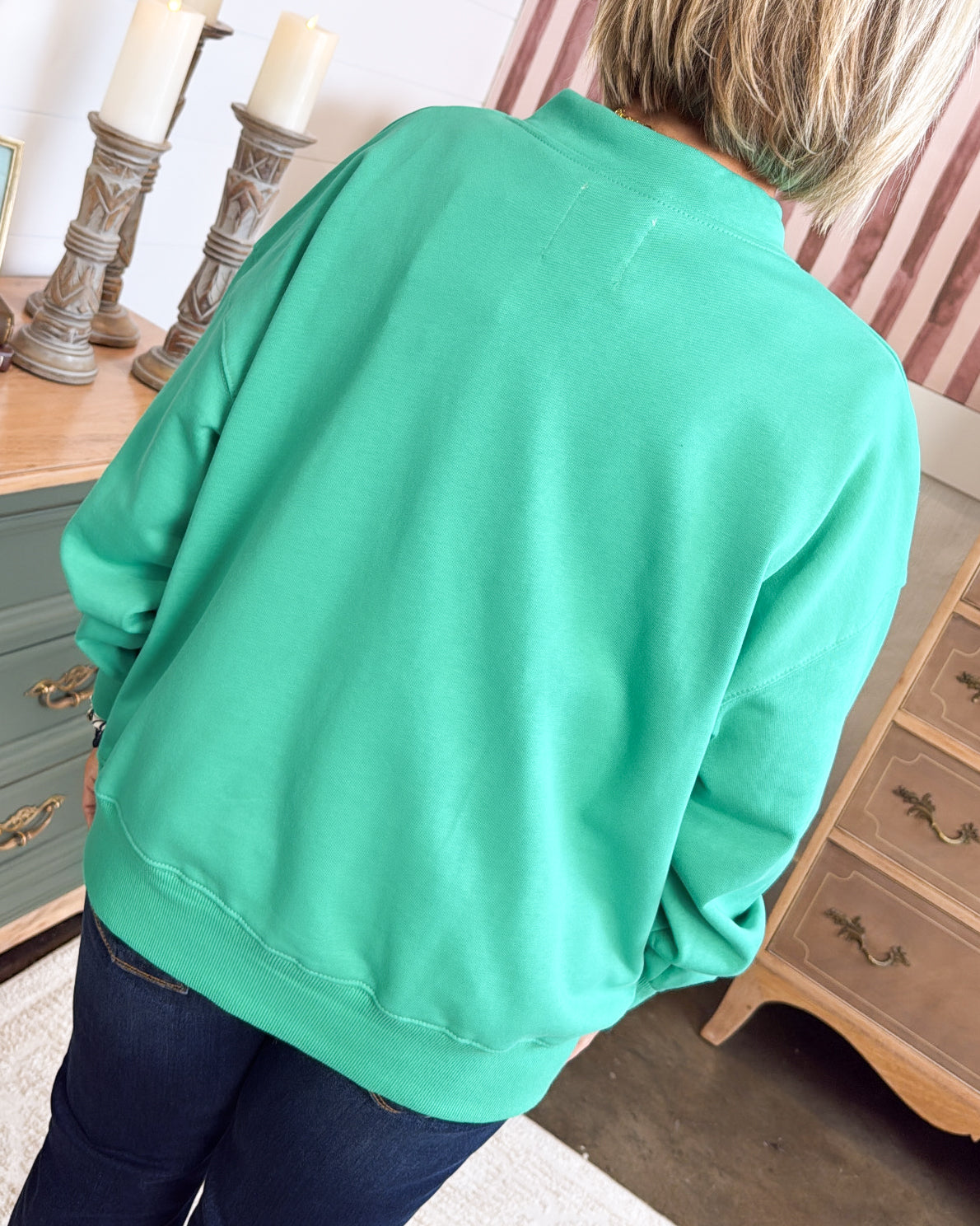 Back view of a jade henley pullover with ribbed hem