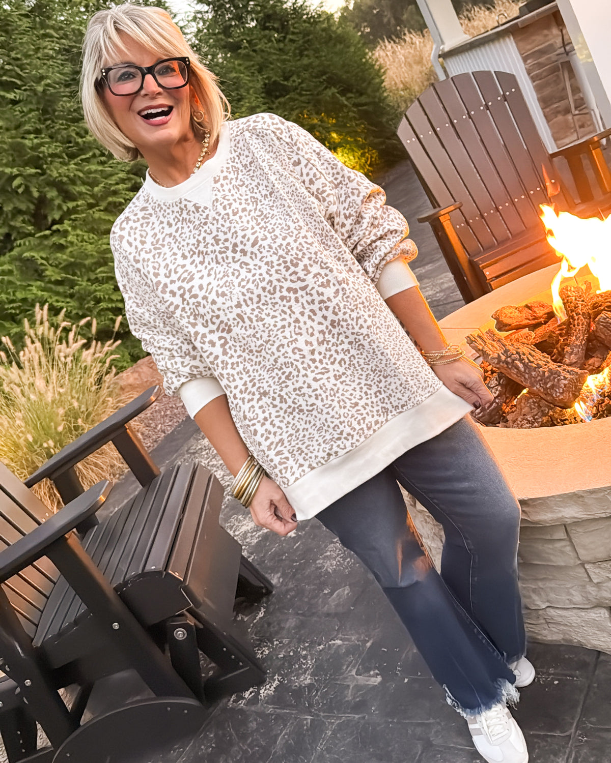 Full-length view of an oversized cream leopard corded pullover styled with flare jeans and white sneakers