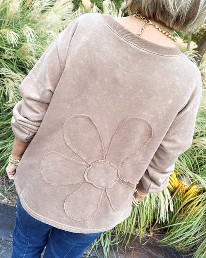 Back view of a brown pullover with a large raised flower applique