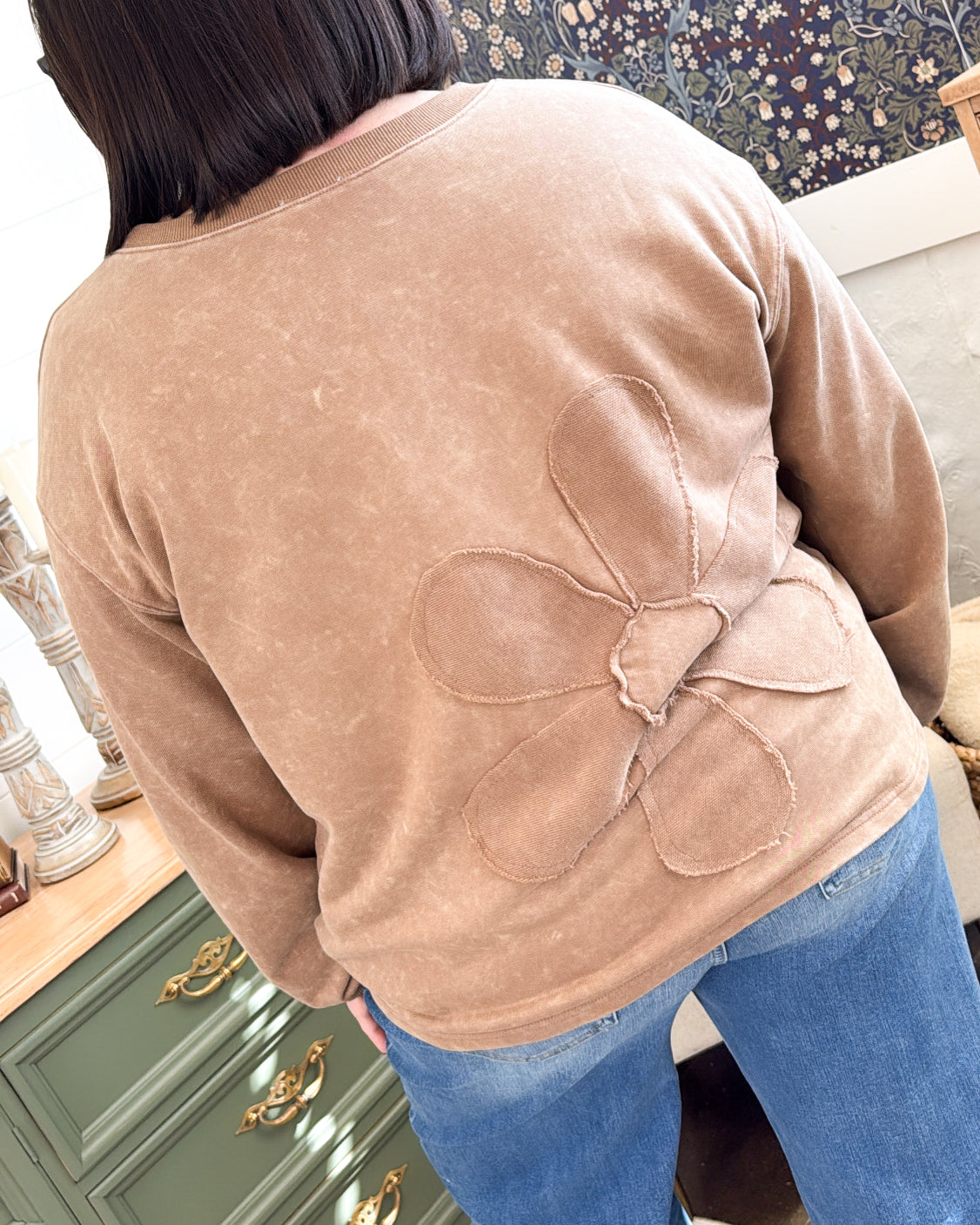 Back view of a brown mixed knit pullover with a stitched flower applique