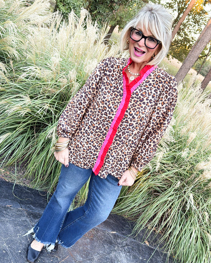 Full-length view of a taupe leopard blouse with red contrast ruffle placket, styled with flare jeans