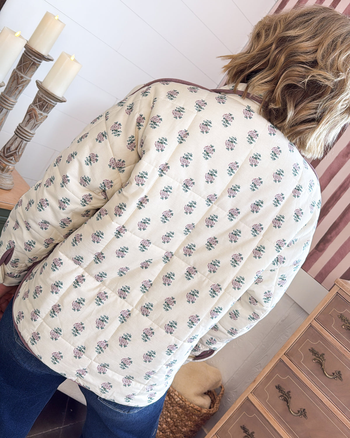 Back view of an ecru floral quilted jacket with mauve piped trim