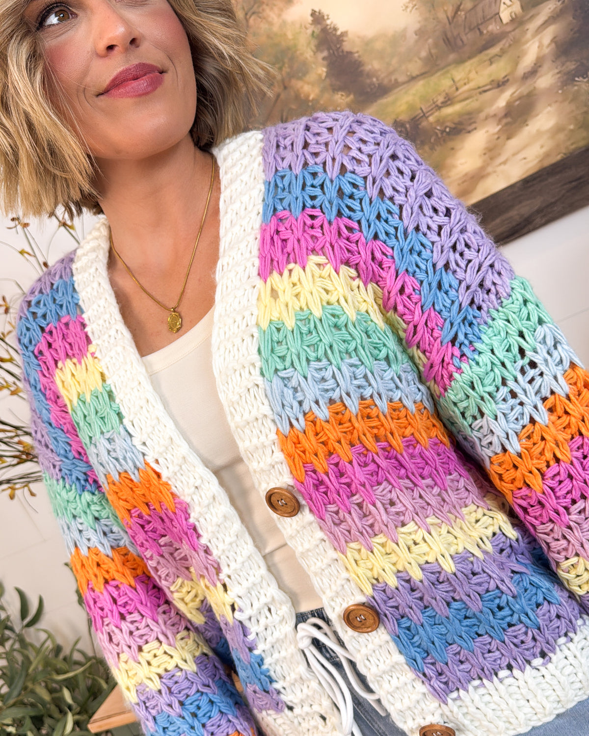Close-up of the crochet cardigan's open-knit pastel stripes, ivory trim, and brown buttons