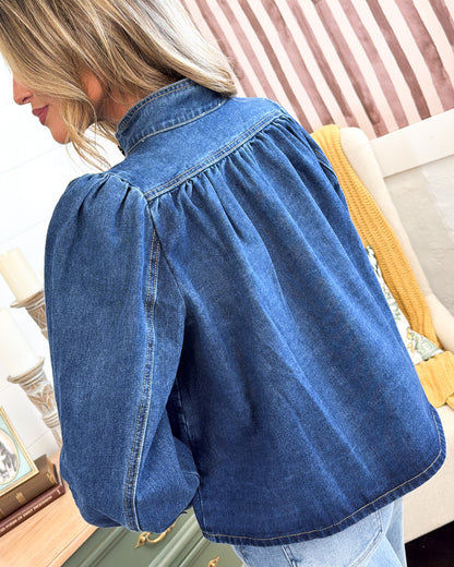 Back view of the medium wash denim jacket showing the pleated yoke and puff sleeves