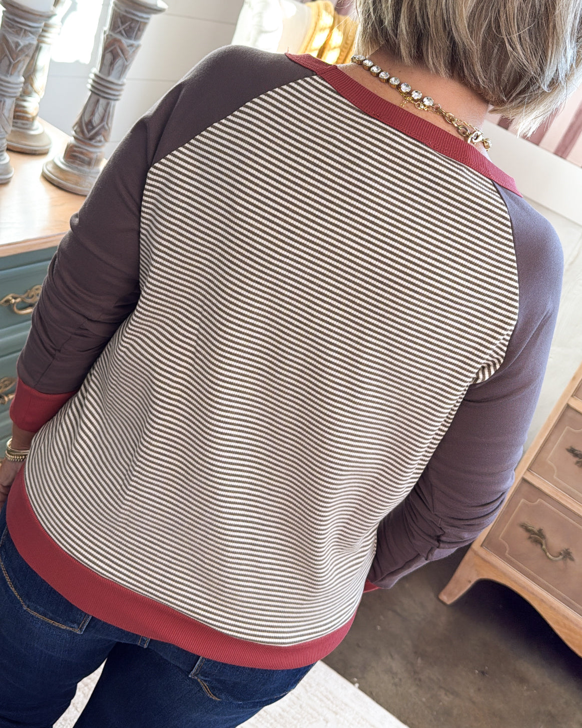 Back view of the striped top with mocha raglan sleeves and a rust red hem band